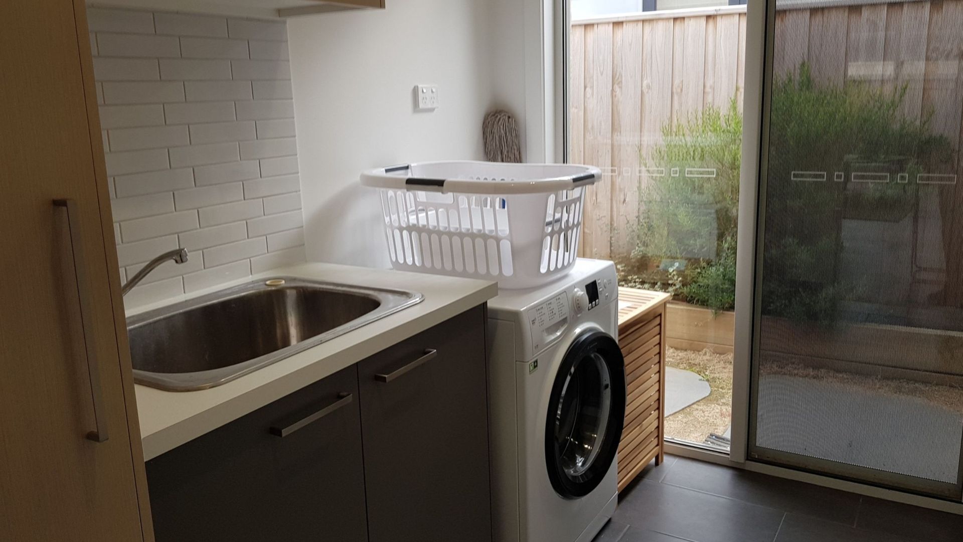A laundry area with a washing machine, a sink, and a basket.