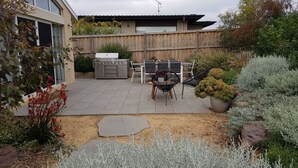 Une terrasse avec un barbecue, des chaises et un pot de fleurs.