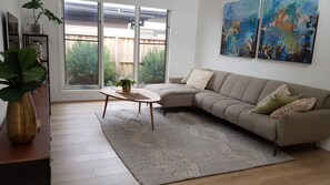 Un salon avec un canapé, une table basse, une grande fenêtre et un tableau accroché au mur.