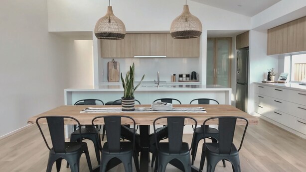 Une cuisine moderne avec un îlot central, des chaises noires et deux lampes suspendues.