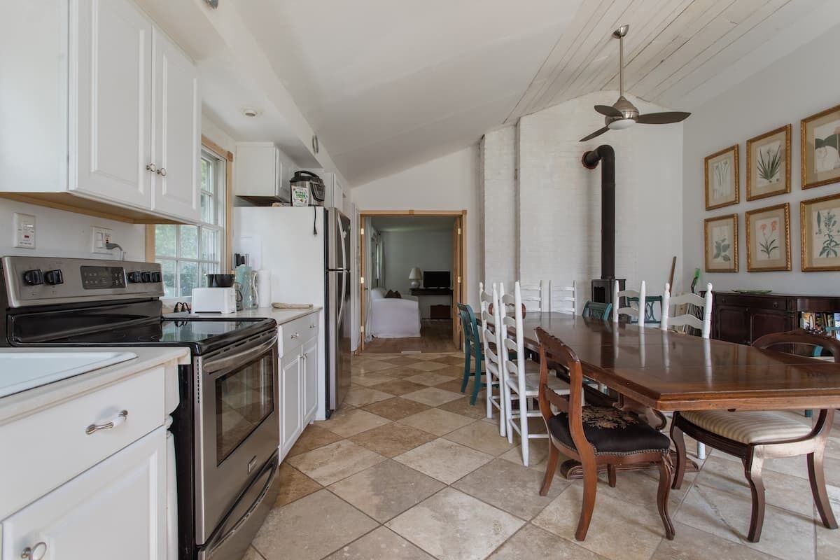 A kitchen with white cabinets, a black stove, and a dining area with a wooden table and chairs.