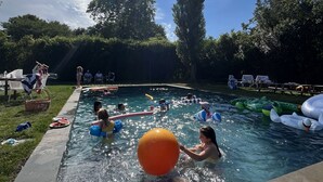 Un espace piscine avec une eau claire, entouré de pelouse et d’arbres.