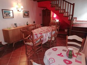 Un coin repas avec une table ronde recouverte d’une nappe à motifs floraux, entourée de chaises en bois.