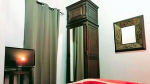 Une chambre à coucher avec un lit, une télévision, une armoire et un miroir au mur.