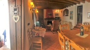 Un coin repas chaleureux avec une table et des chaises en bois, une cheminée et un escalier menant à un niveau supérieur.
