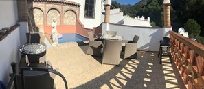 Une terrasse sur le toit avec une piscine, du mobilier d’extérieur et une statue.