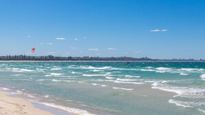 A beach with clear blue water, a sandy shore, and a distant city skyline. - Splash House at Kingscliff - Pet Friendly with Pool (KINGSCLIFF)