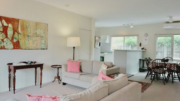 A living room with a sofa, a coffee table, a lamp, and a painting on the wall.