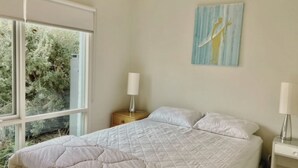 A bedroom with a bed, a nightstand, a lamp, and a painting on the wall.