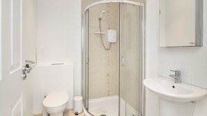 A modern bathroom with a glass-enclosed shower, a toilet, and a sink. - Haven Apartments at Eglantine Avenue (Belfast)