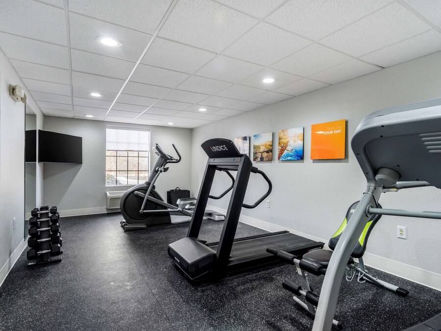 Una palestra con tapis roulant, manubri e uno specchio.