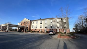 A multi-story building with a covered entrance and a parking area.