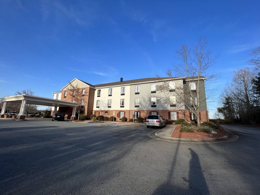 A multi-story building with a covered entrance and a parking area.