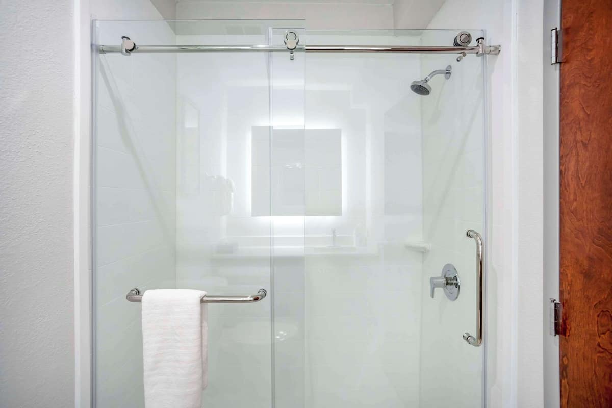 A glass-enclosed shower with a towel rack and grab bars.