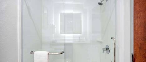A glass-enclosed shower with a towel rack and grab bars.