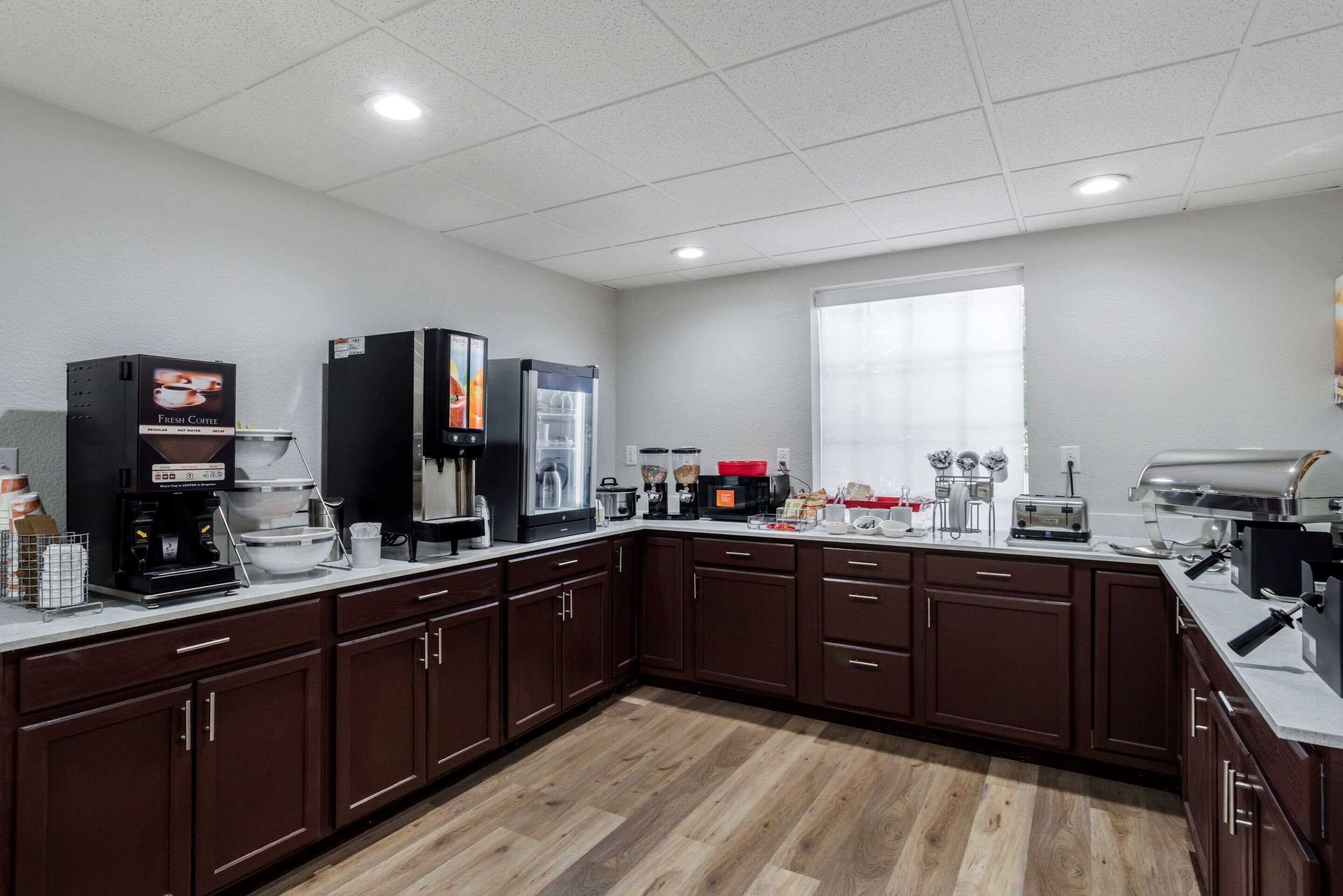 A modern kitchen with dark wooden cabinets, a coffee station, and a large window.