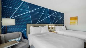 A hotel room with a large bed, two bedside tables, a chair, and a wall with a geometric pattern.