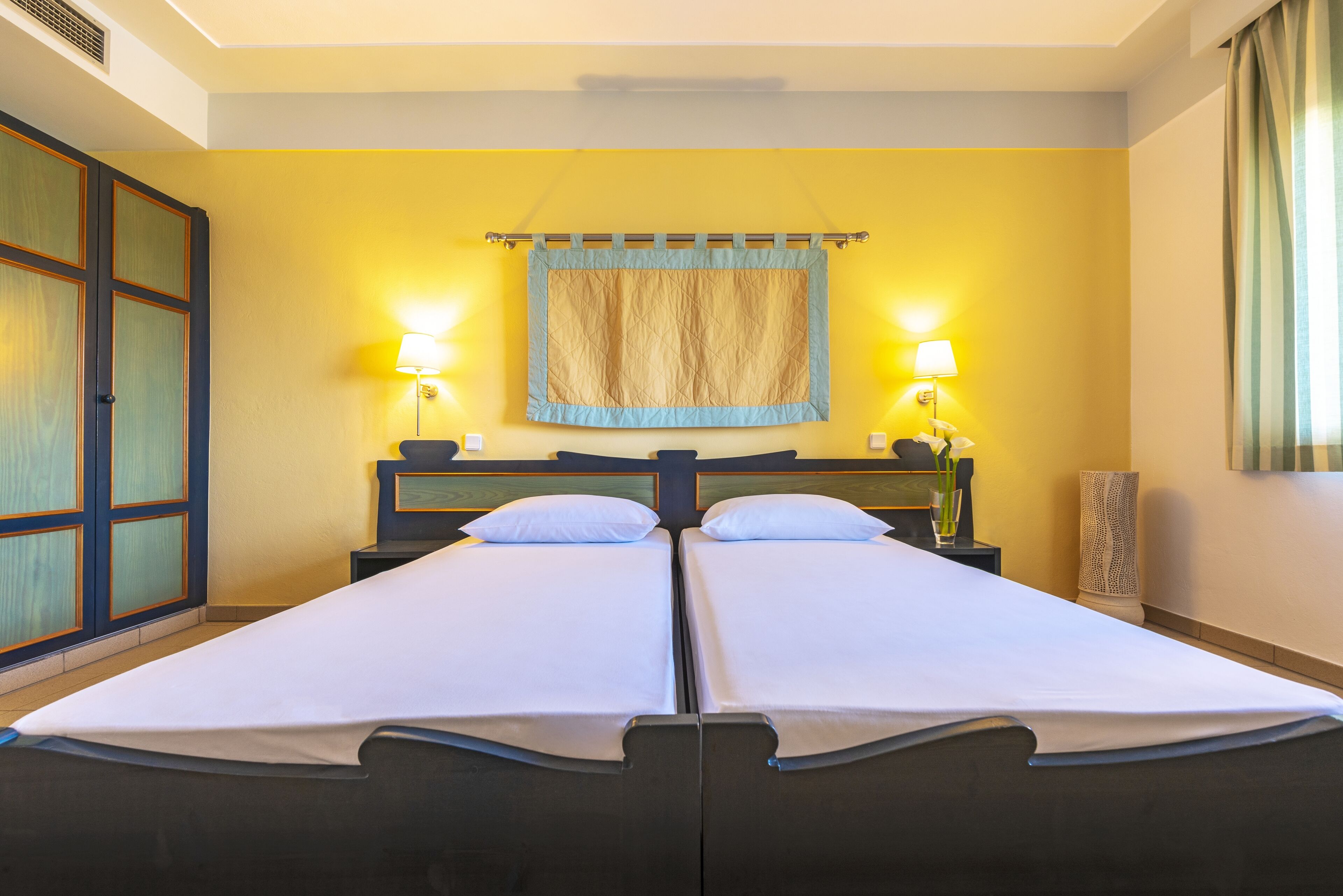 A double bed with white linens, two bedside lamps, and a curtain.
