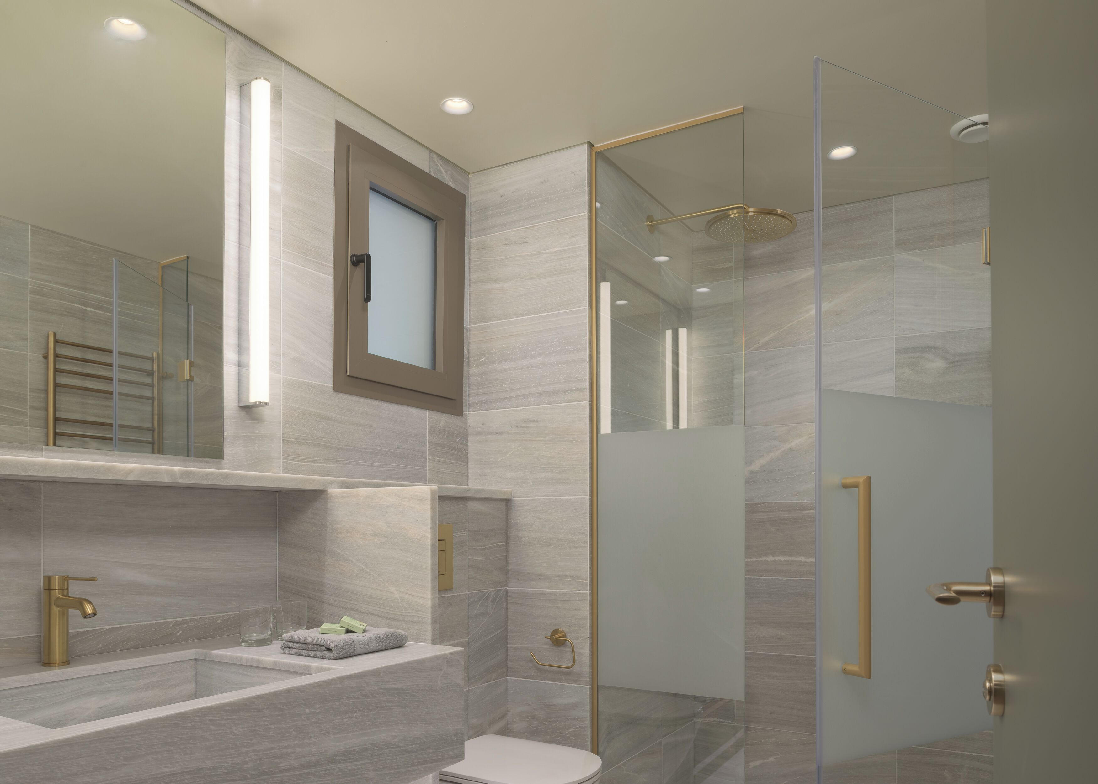A modern bathroom with a glass-enclosed shower, a large mirror, and a vanity with a sink and towel rack.
