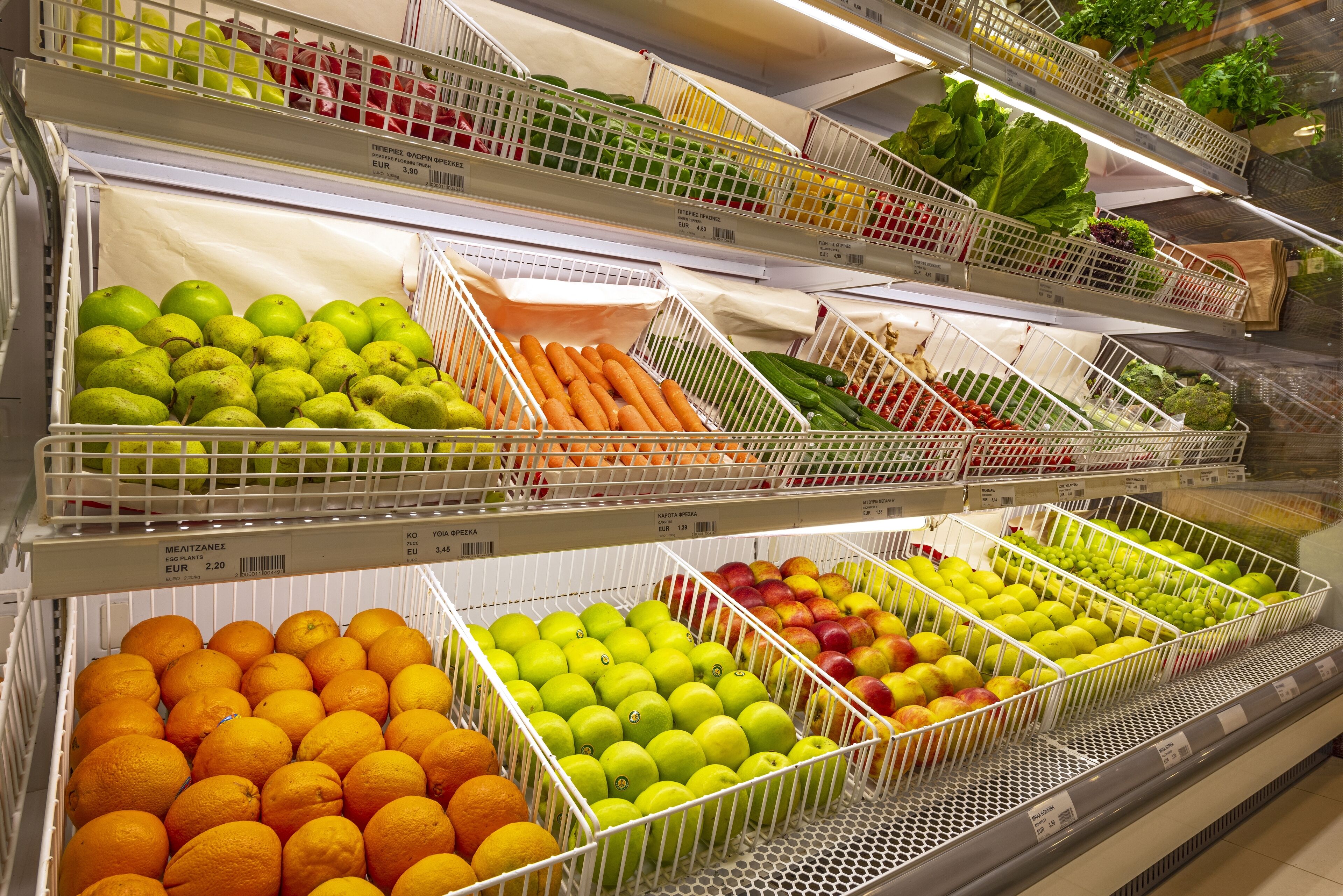 A grocery store with various fruits and vegetables in wire baskets.
