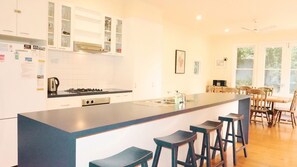 Een moderne keuken met een centraal eiland, barkrukken en een eethoek met houten stoelen.
