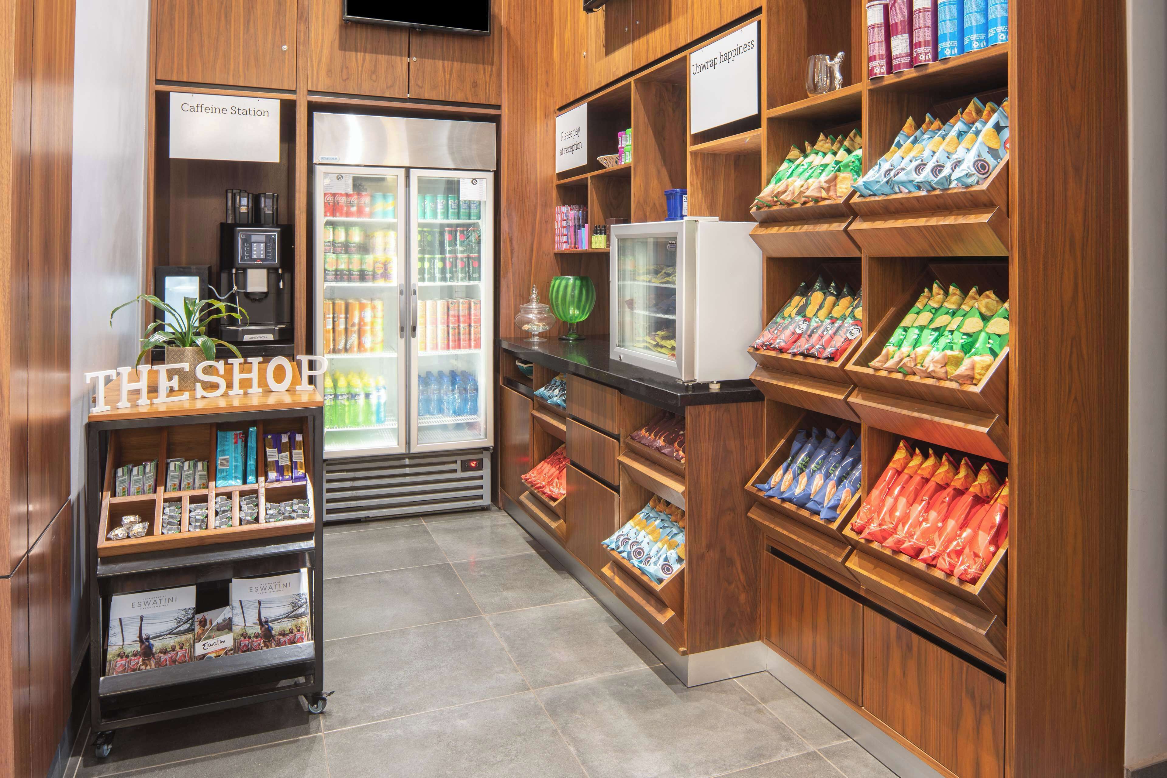 Una tienda con estantes llenos de refrigerios y bebidas, un refrigerador y una estación de café.