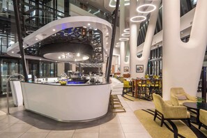 A modern interior with a central counter, seating area, and high ceilings with circular lighting. - Hilton Garden Inn Mbabane (Mbabane)
