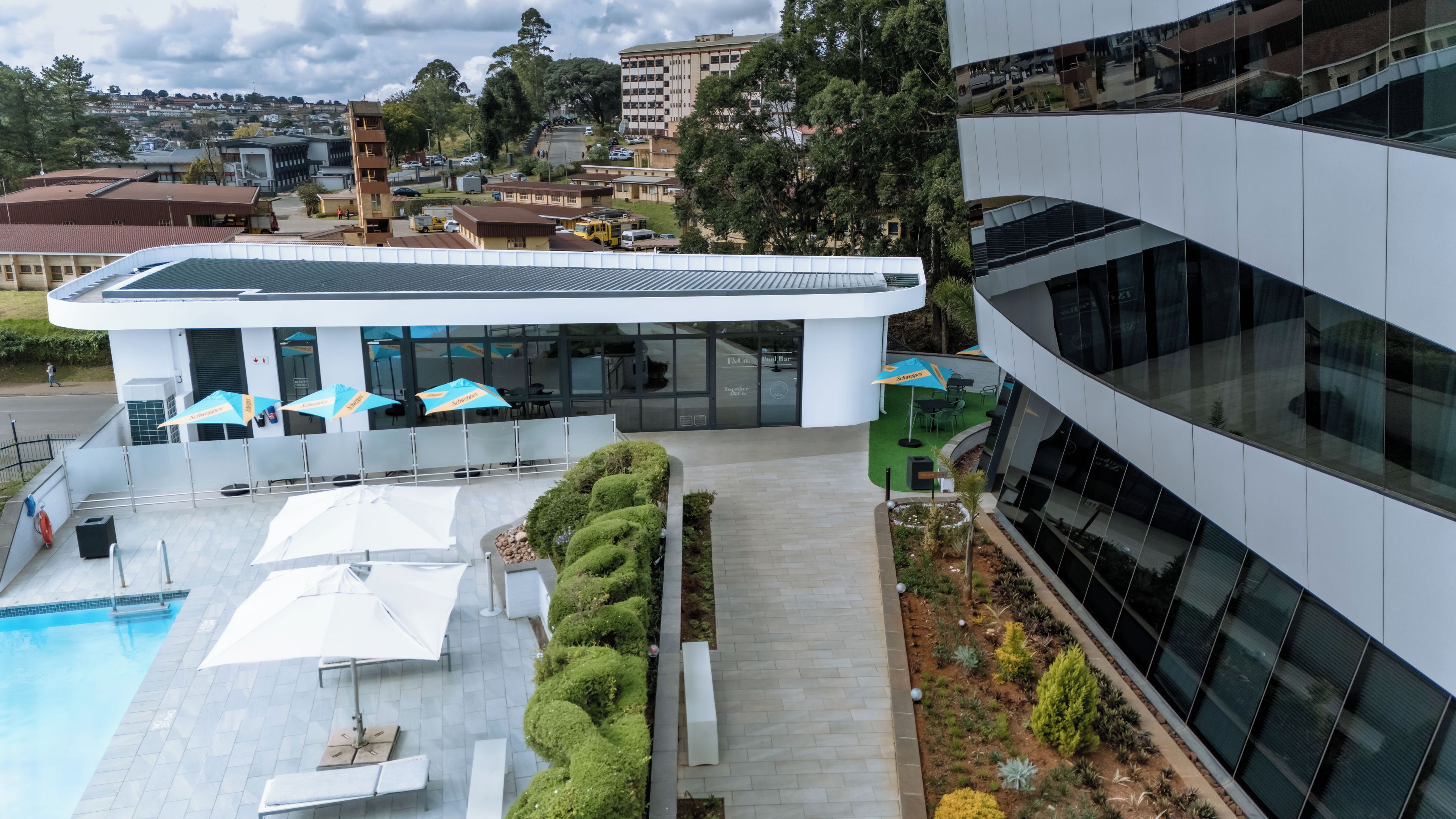 A modern building with a pool area, outdoor seating, and a well-maintained garden.