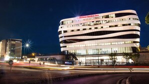En moderne bygning med Hilton Garden Inn-skilt, der har en buet facade og mange vinduer.