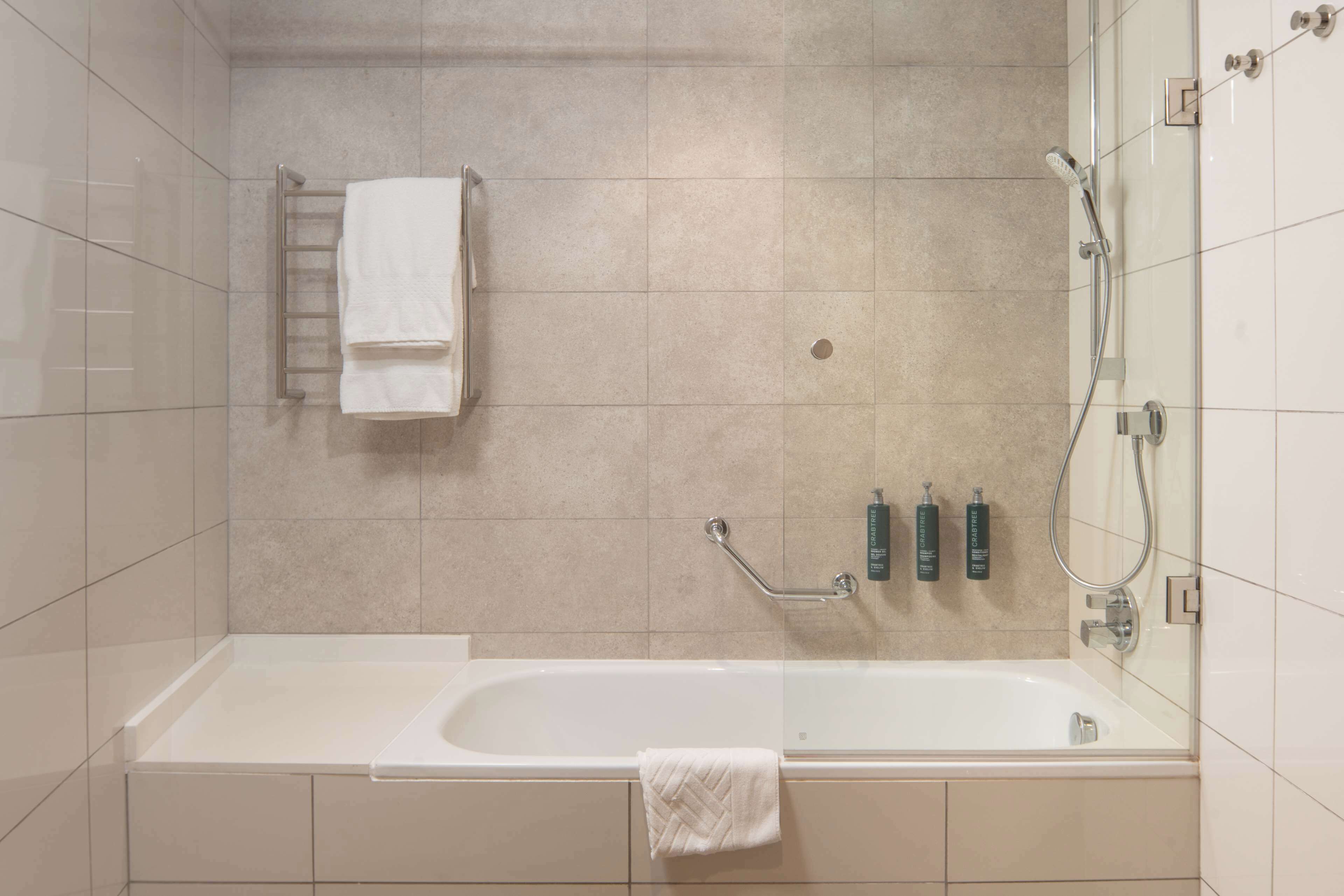 A modern bathroom with a bathtub, a towel rack, and a shower area.