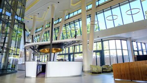 En rummelig lobby med højt til loftet, store vinduer og moderne lysarmaturer.