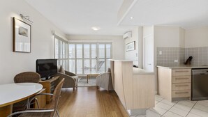 A modern apartment with a dining area, a living room with a TV, a kitchen with a dishwasher, and large windows. - Resort on the Beach 4302 with resort Pool (KINGSCLIFF)