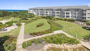 A modern hotel with a landscaped garden, multiple balconies, and a view of the ocean. - Resort on the Beach 4302 with resort Pool (KINGSCLIFF)
