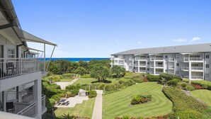 A multi-story hotel with balconies, a well-maintained lawn, and a view of the ocean. - Resort on the Beach 4302 with resort Pool (KINGSCLIFF)