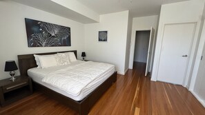 A bedroom with a bed, nightstands, a painting, and a door. - Amaroo by the beach and Swan Bay (Queenscliffe)