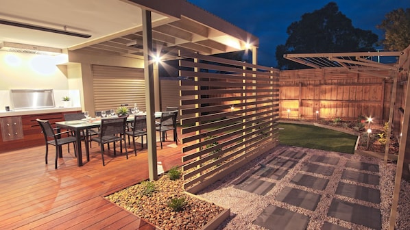 An outdoor patio with a dining area, a wooden fence, and a small lawn.