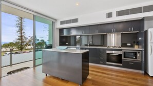Una cocina moderna con armarios oscuros, electrodomésticos de acero inoxidable y una isla grande.