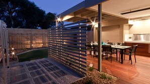 An outdoor patio with a dining table and chairs, a grill, and a wooden fence. - Taworri at Swan Bay in Queenscliff (Queenscliff)