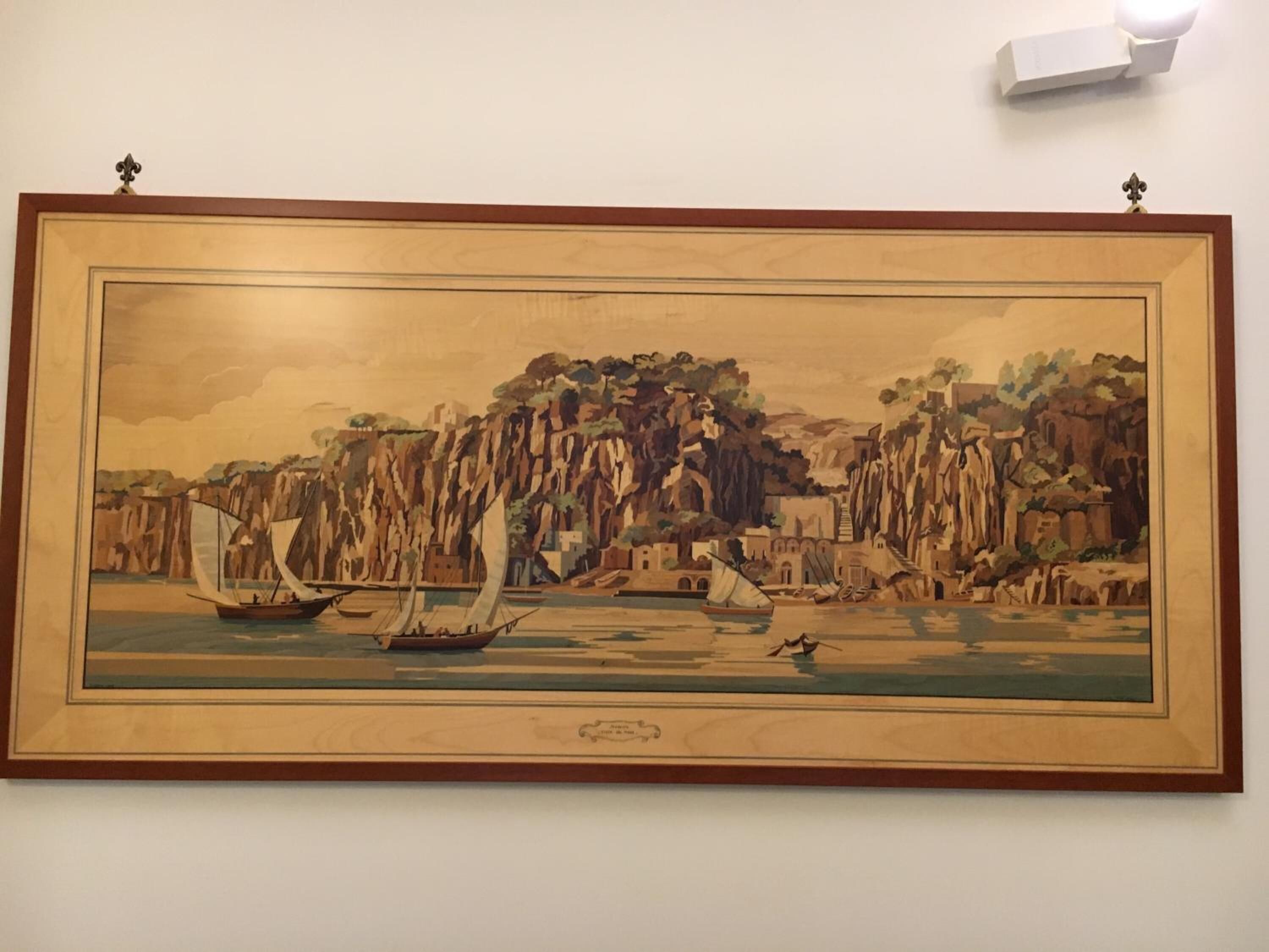 A framed landscape painting of a coastal scene with cliffs and boats.