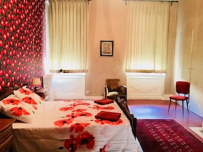 Un dormitorio con cama, dos sillas, cómoda y radiador.