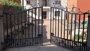 Un cancello conduce a una proprietà residenziale con un edificio bianco e un tetto rosso.
