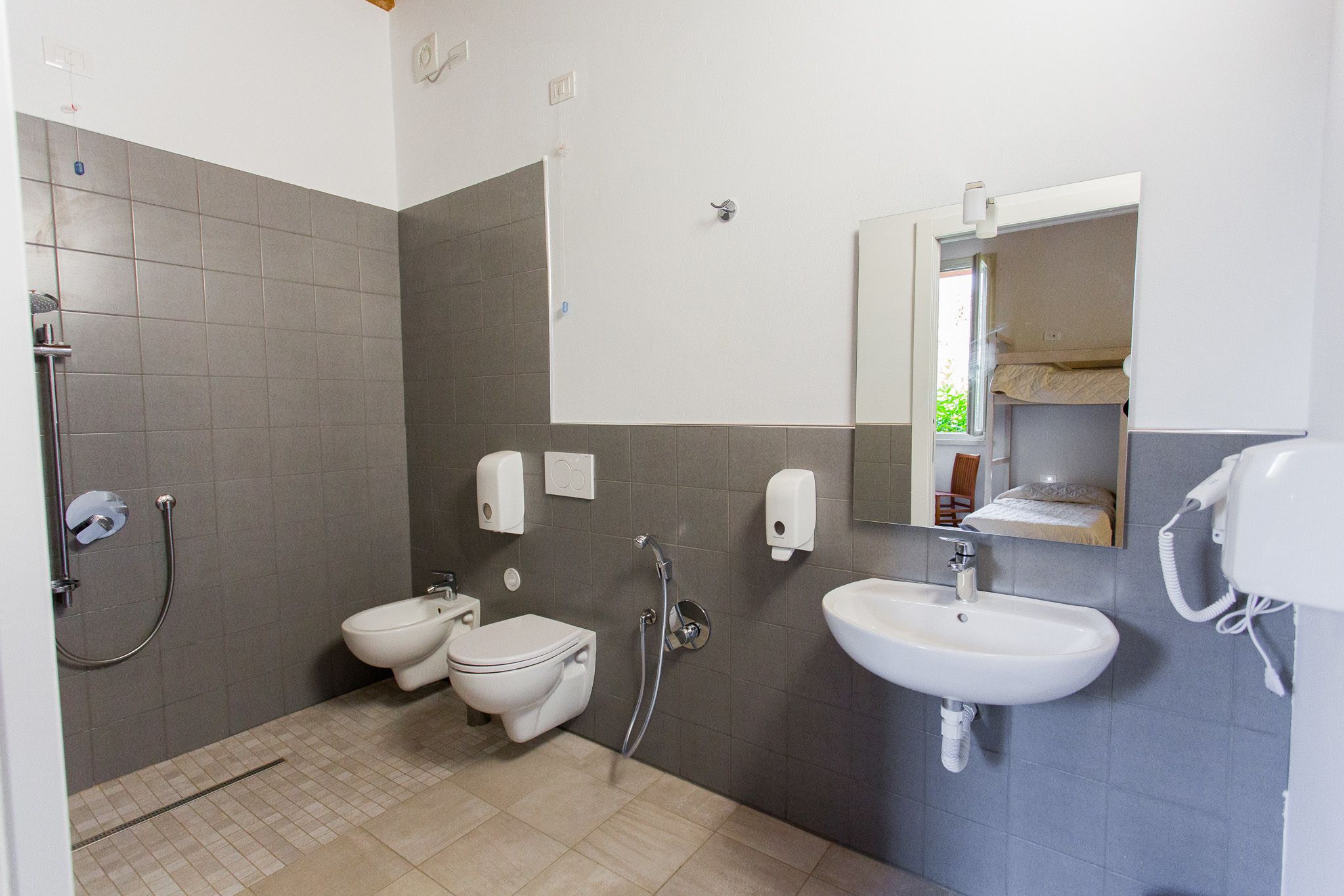 A modern bathroom with a toilet, bidet, shower, and sink.