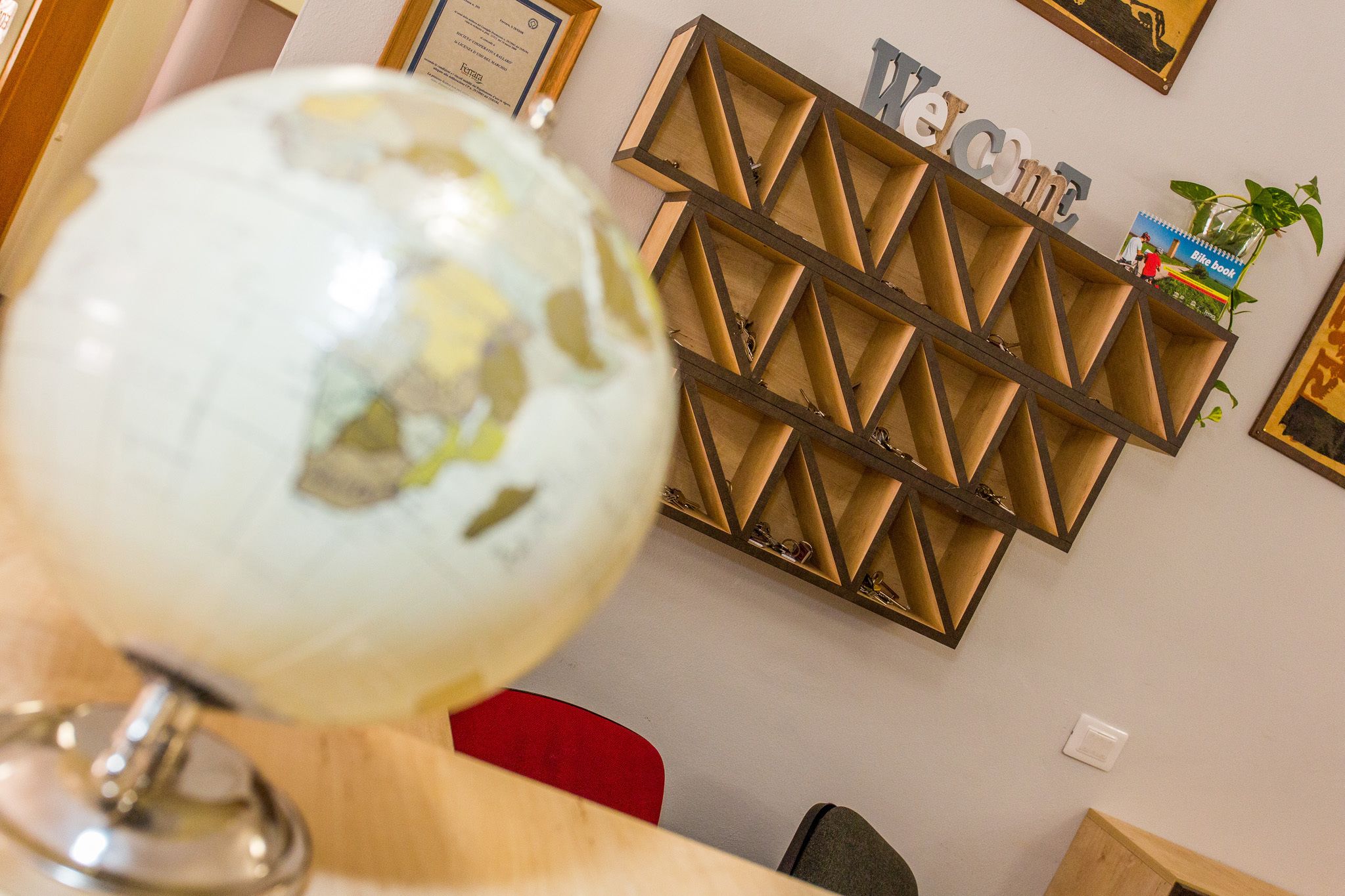 A globe on a desk, a wooden shelf with a 'WELCOME' sign, and a blue book on the shelf.