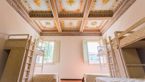 Una habitación con literas, techo decorativo y dos ventanas.