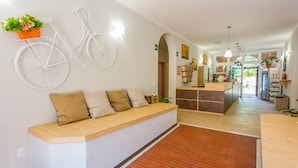 Una zona de recepción con un banco de madera, una obra de arte mural de bicicleta blanca, un mostrador de recepción y un suelo de ladrillo.