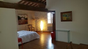 Une chambre à coucher avec un lit, une chaise, une lampe sur pied, une petite table et un tableau au mur.
