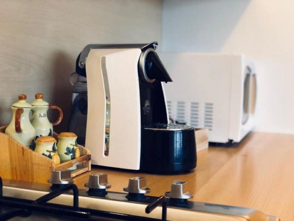 Una cocina con cafetera y microondas sobre la encimera.