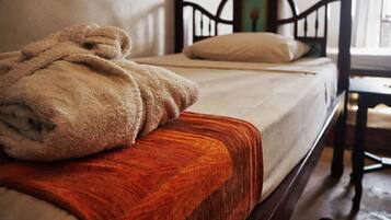 A bed with a wooden headboard, a beige blanket, and a wooden footboard.