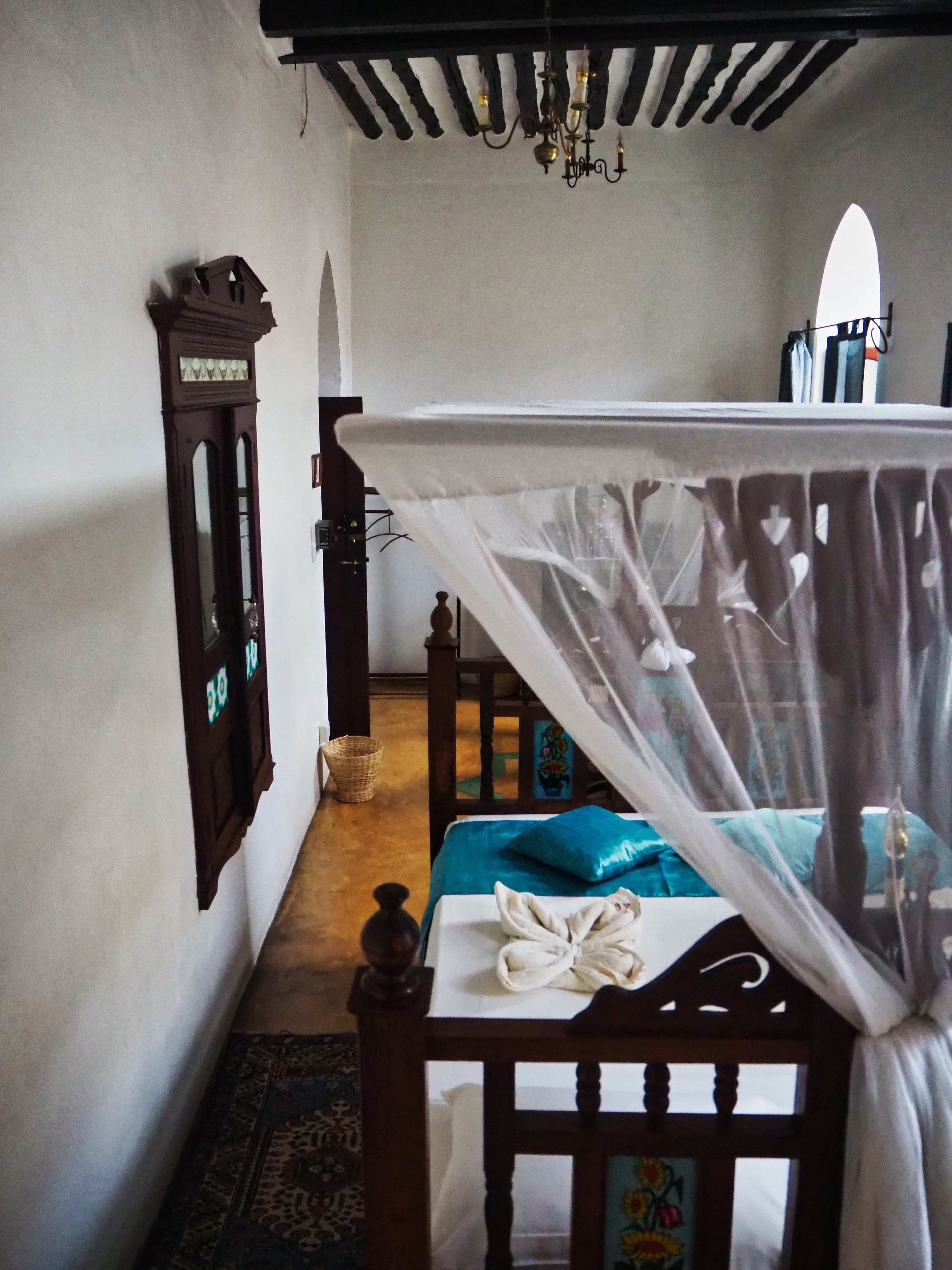 A bedroom with a wooden bed, a nightstand, a mirror, and a chandelier.