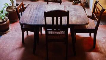 A wooden dining table with chairs, surrounded by potted plants.